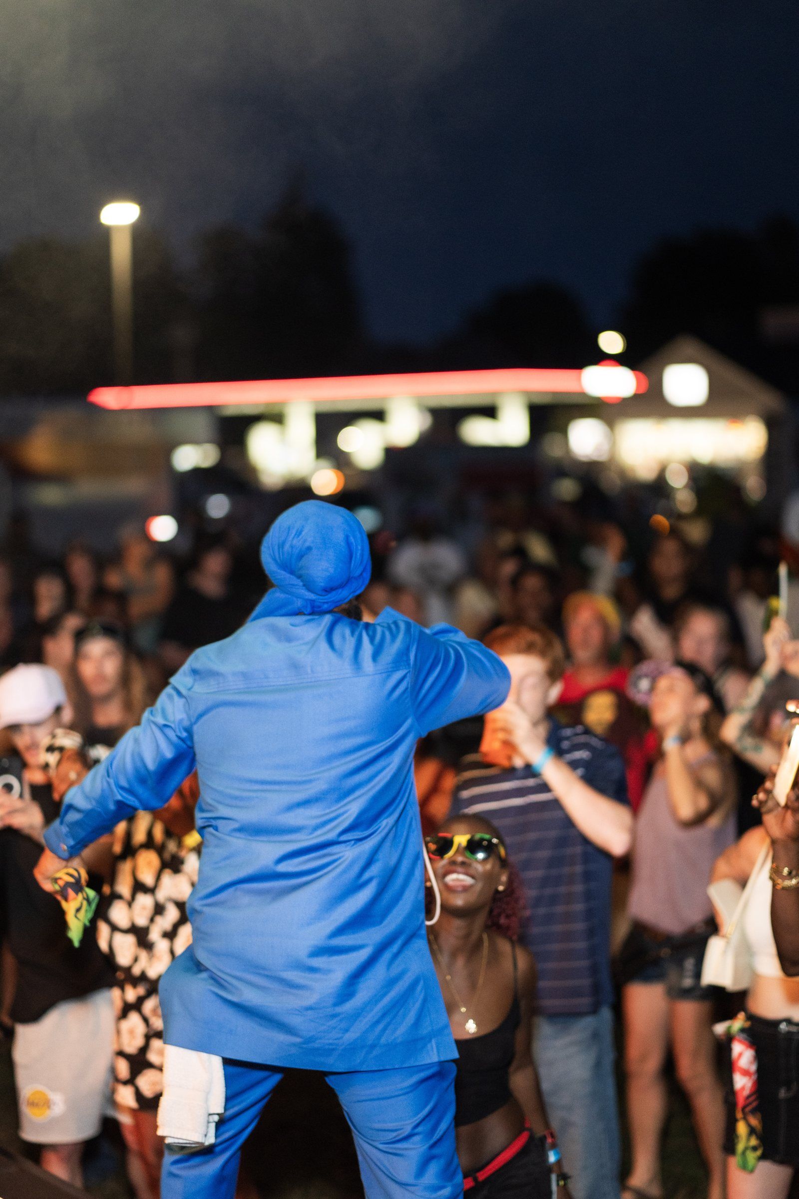 Warrior King in blue facing a packed crowd after dark, 2024