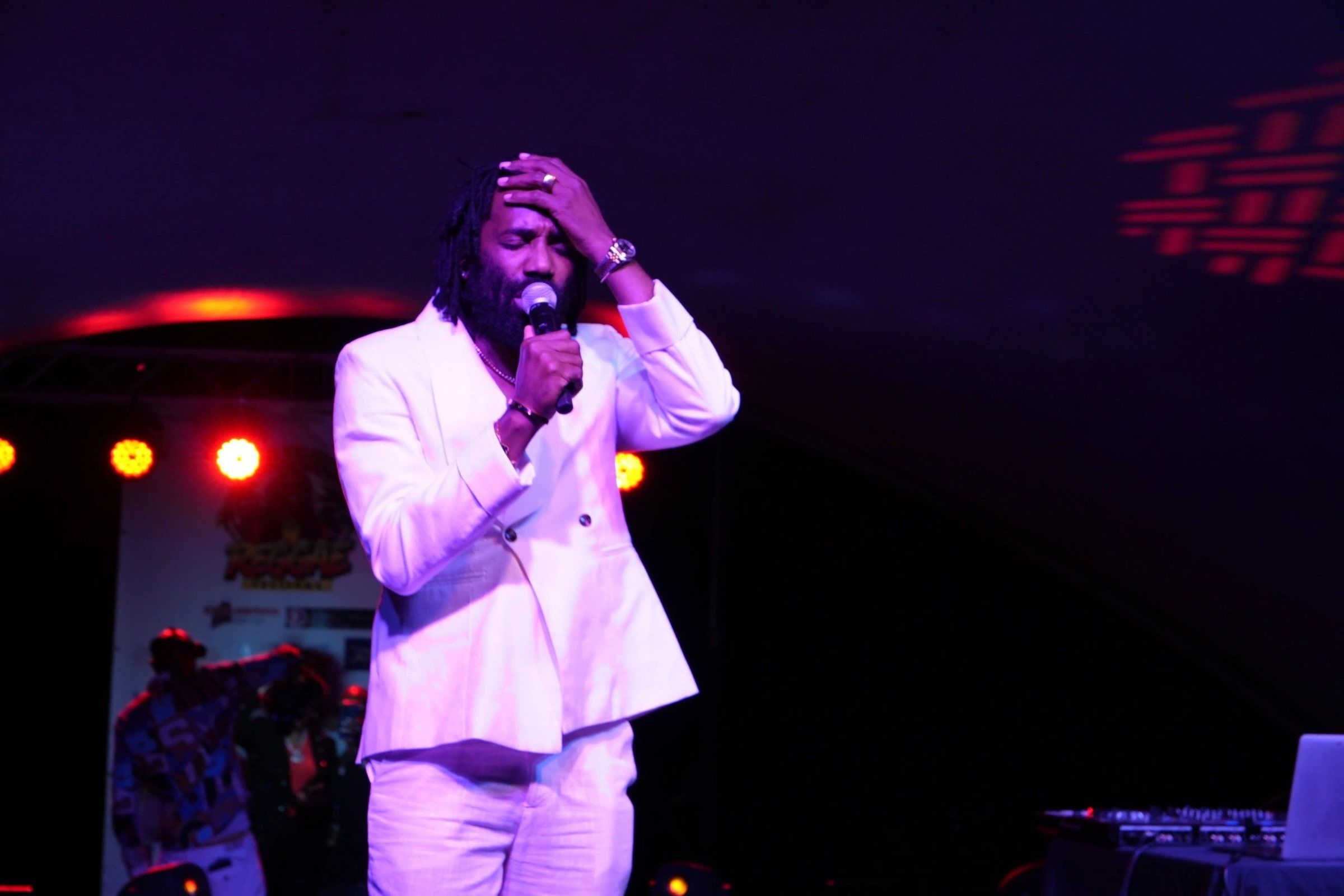 Ginjah in a white suit on stage under pink and red lights, closing the 2025 festival