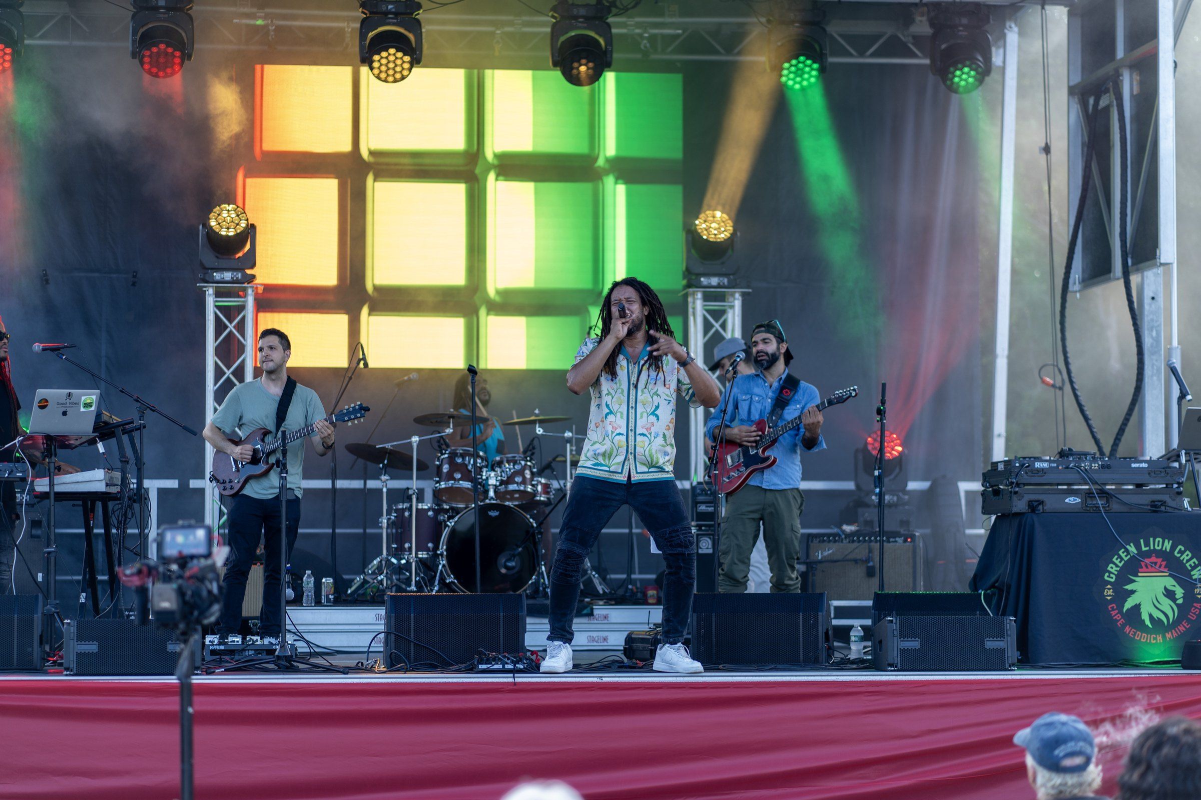 Mighty Mystic and his band on the Culture Reggae Festival stage in front of a red, gold and green light wall, 2024